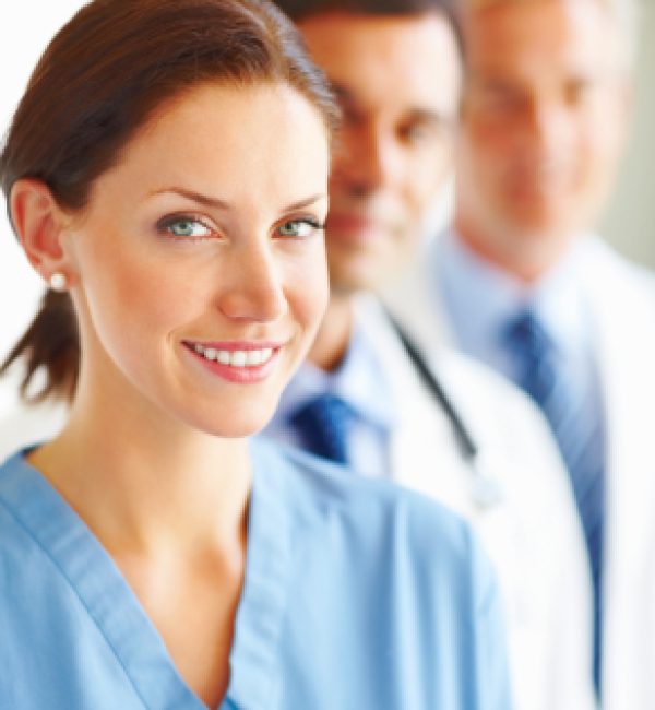 Portrait of a young nurse with doctors at the background